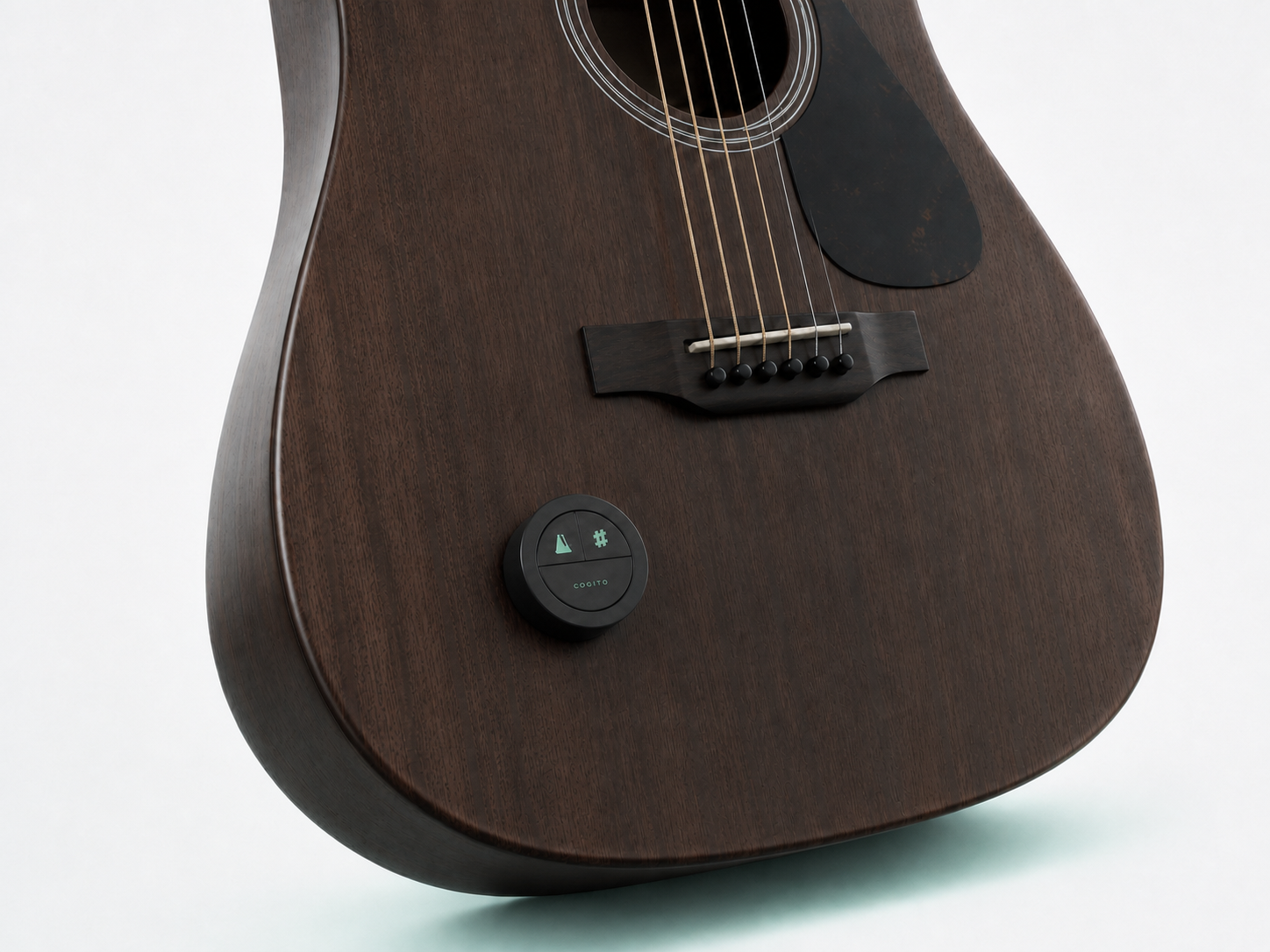 Round COGITO remote attached to the lower face of a six-string guitar